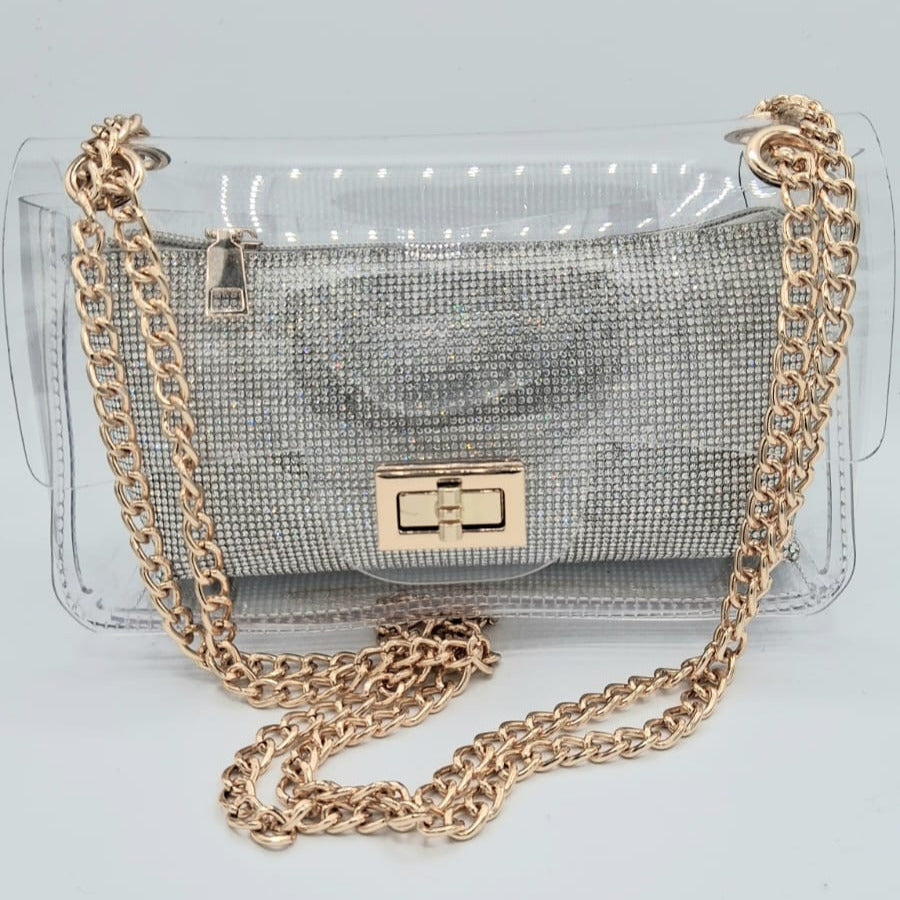 Cartera transparente con clutch interior plateado de cristales y cadena metálica dorada.