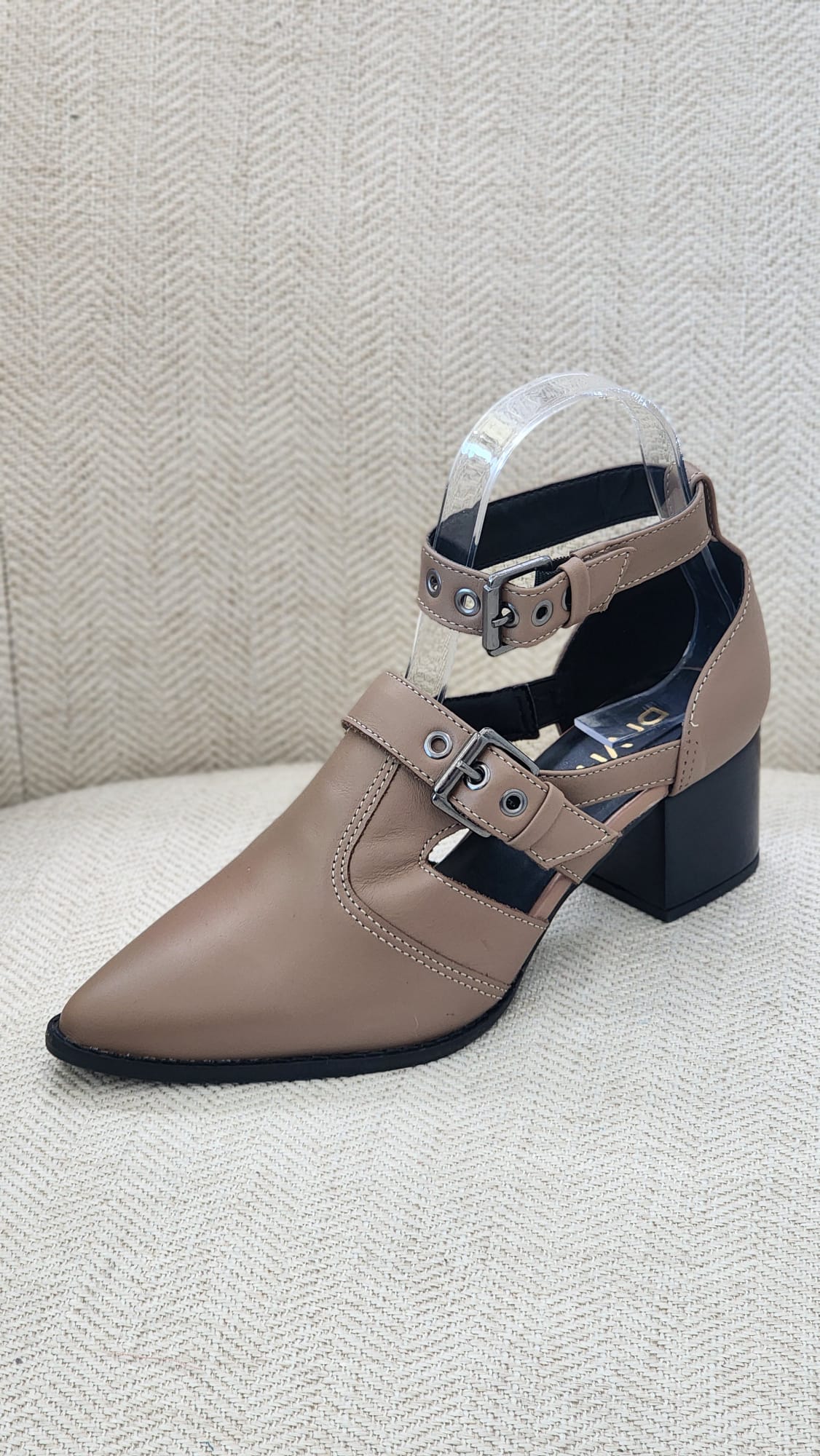 Vista lateral de zapato beige con dos correas al empeine y tobillo, hebillas plateadas y tacón bloque negro.