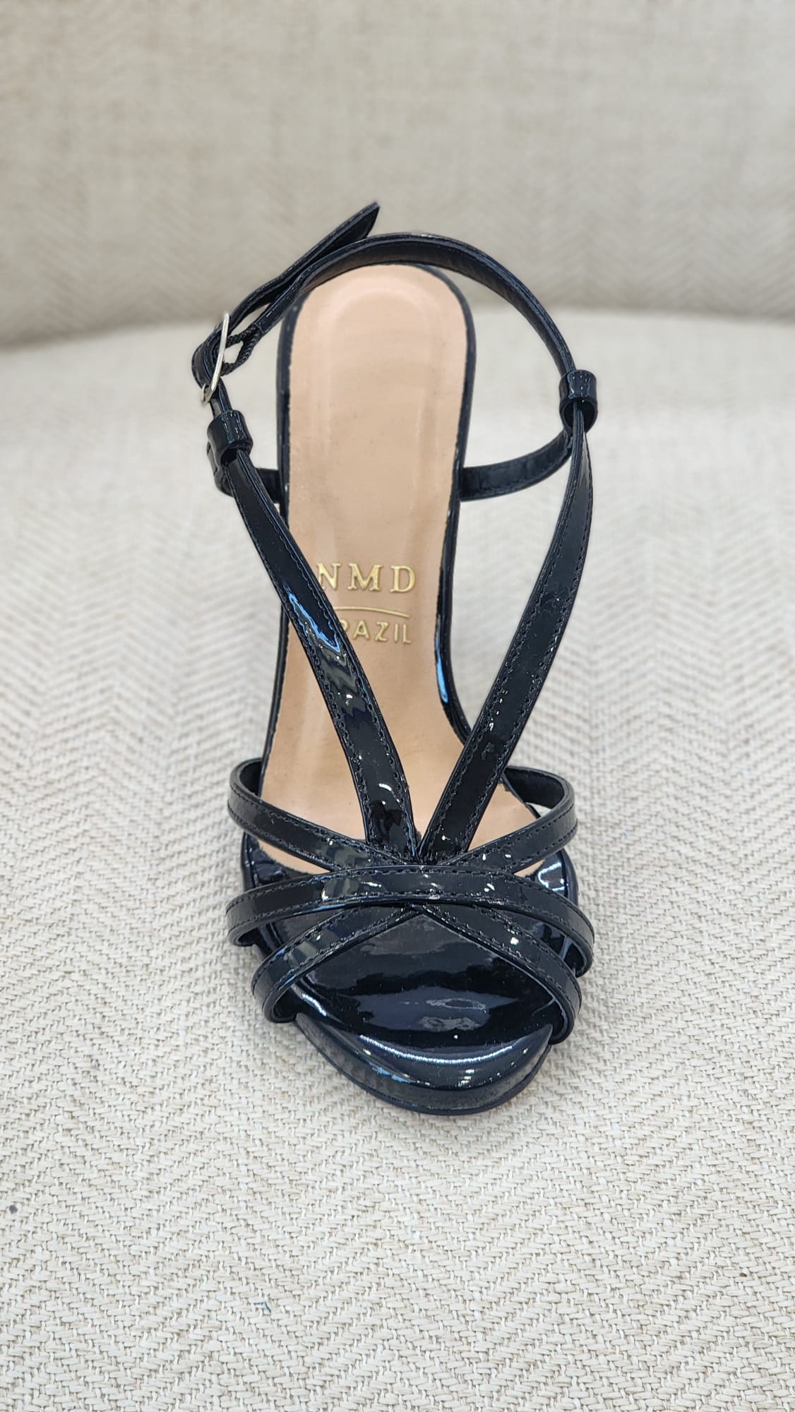 Vista frontal de sandalia negra en charol con diseño elegante de tiras cruzadas.