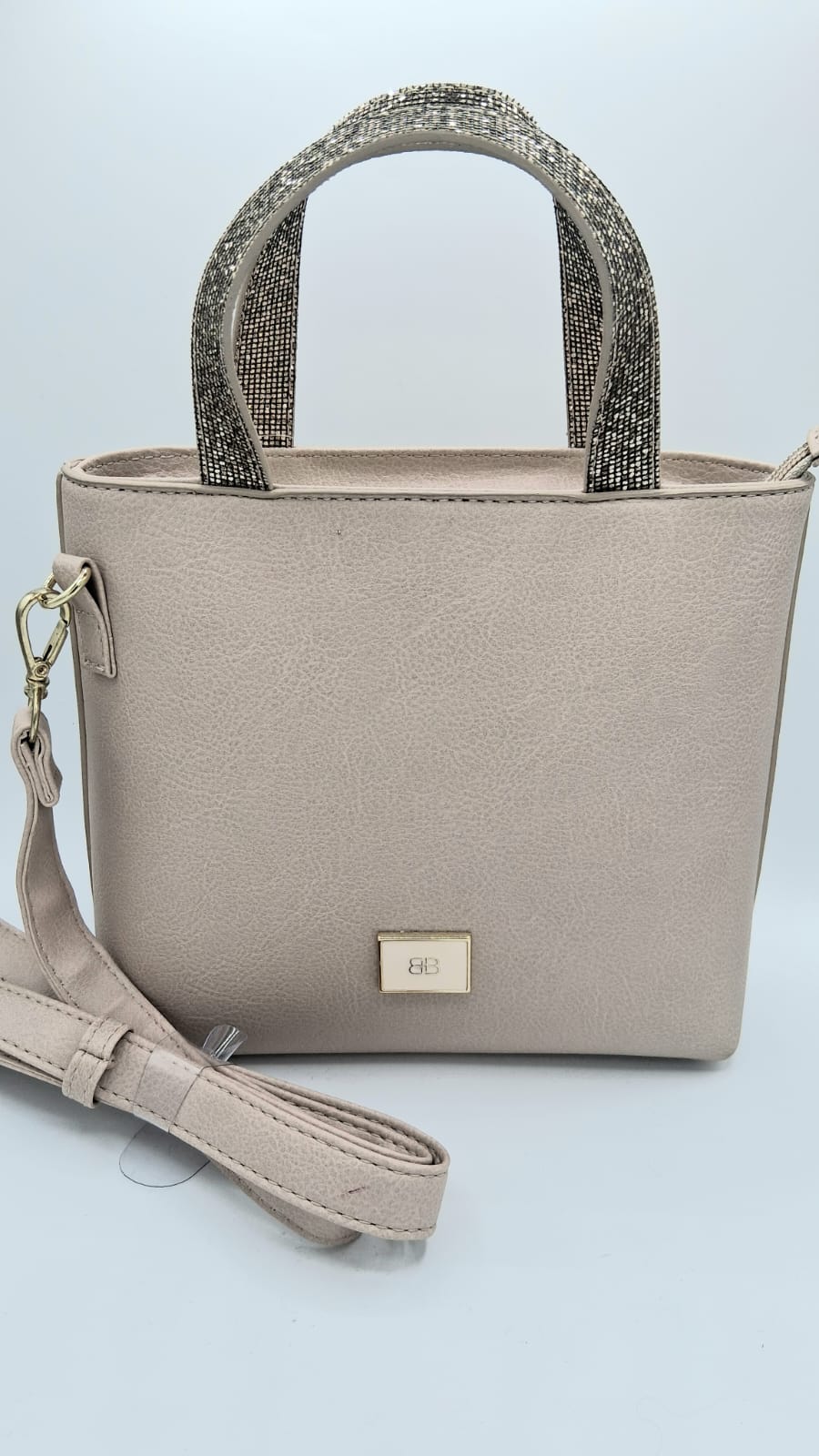 Cartera beige con agarraderas brillantes plateadas y correa larga removible.