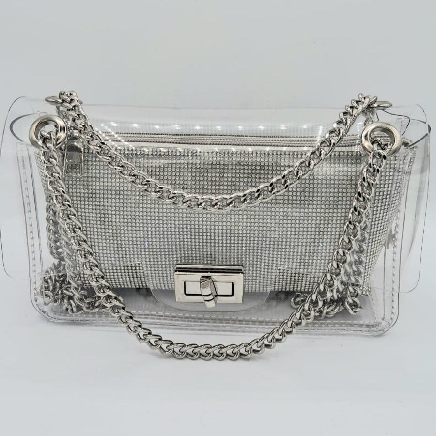 Cartera transparente con clutch interior plateado de cristales y cadena metálica plateada.