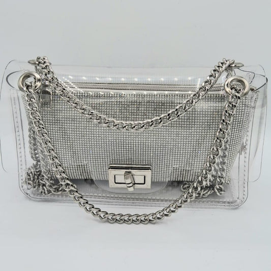 Cartera transparente con clutch interior plateado de cristales y cadena metálica plateada.