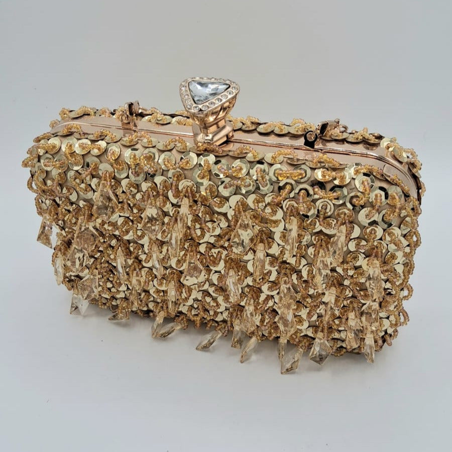 Clutch rígido dorado con asa metálica y broche joya, lentejuelas y pedrería colgante.
