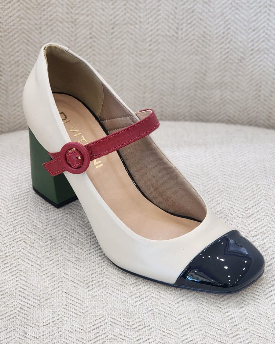 Vista lateral de zapato elegante off white con detalles en negro y rojo.