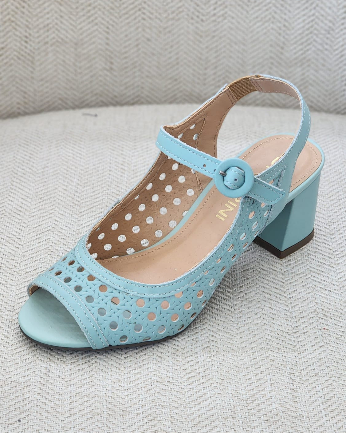 Vista lateral de sandalia menta con punta abierta y acabado calado ligero, tacón bloque cómodo.