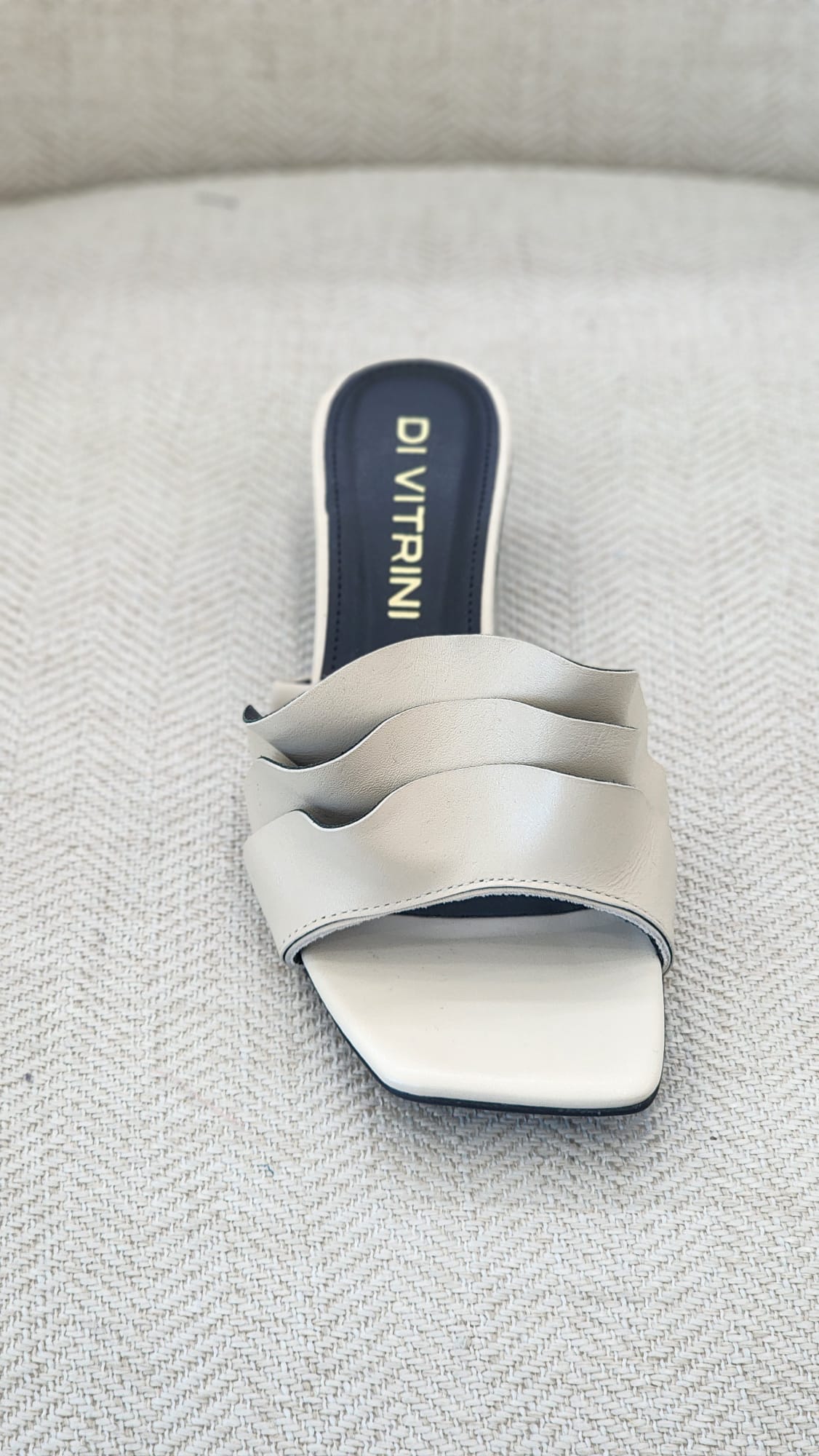 Vista frontal de sandalia off white con diseño minimalista de tiras onduladas y estilo slip-on.