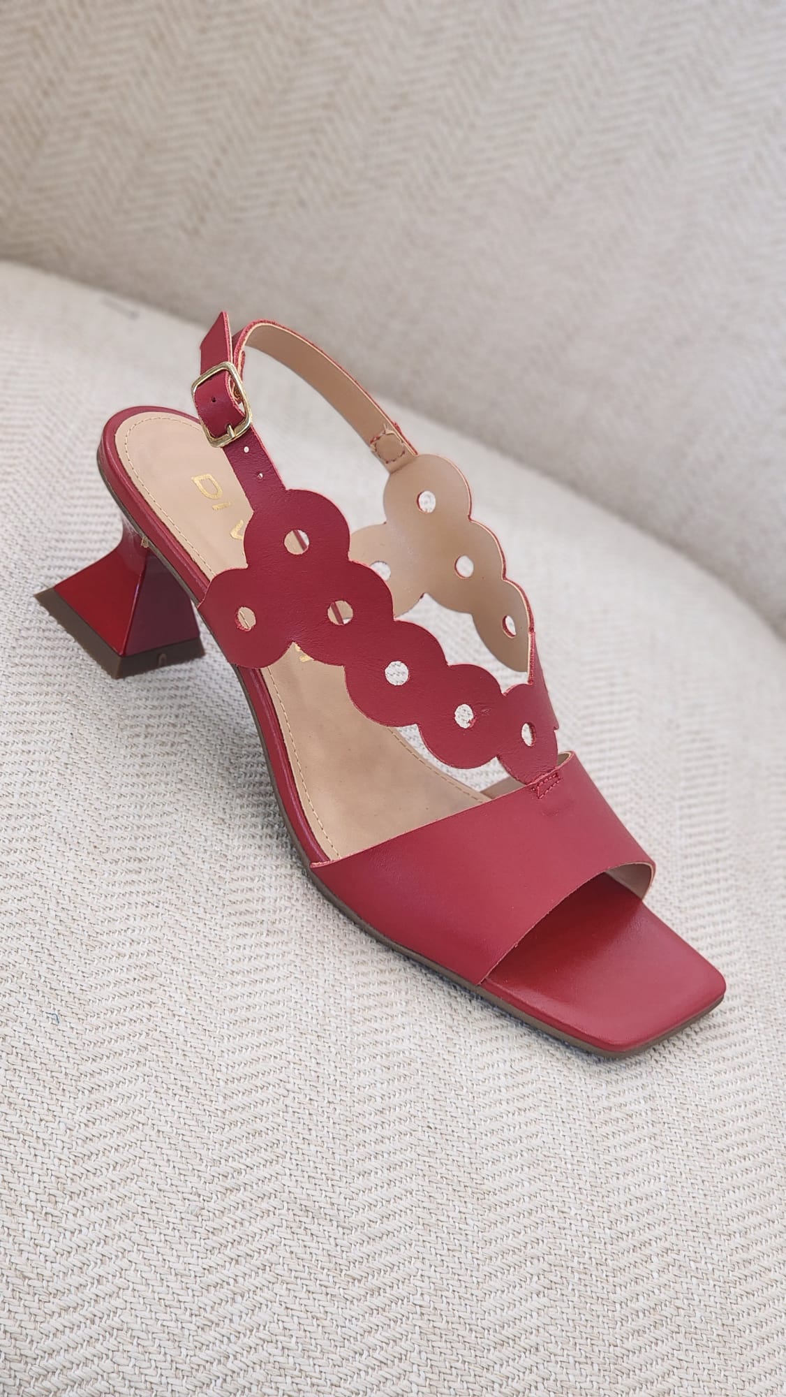 Vista lateral de sandalia vino fucsia con tacón geométrico medio y diseño calado moderno.