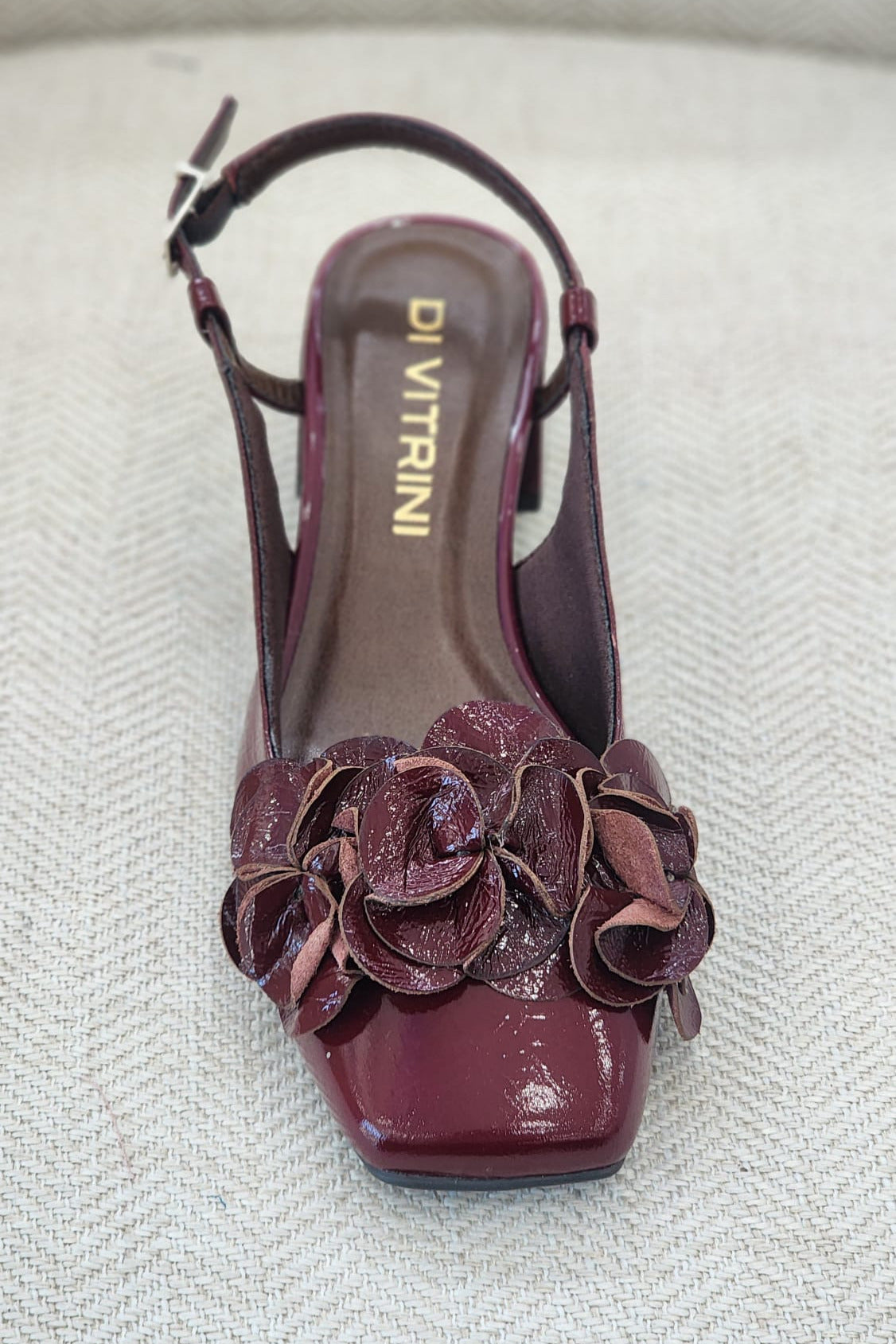 Zapato slingback en charol burgundy con flores en la parte frontal.