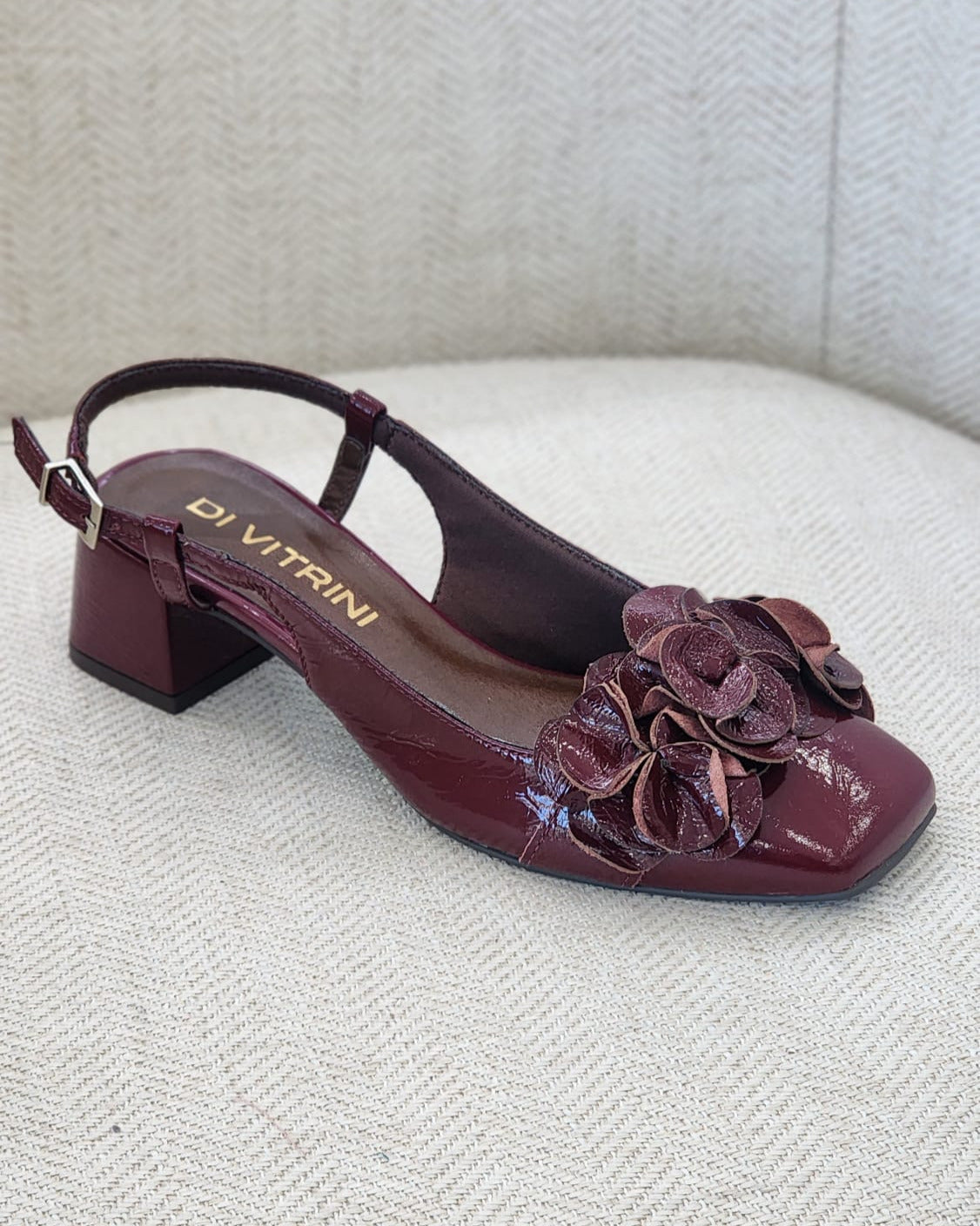 Vista lateral de zapato burgundy con tacón bajo y diseño floral elegante.