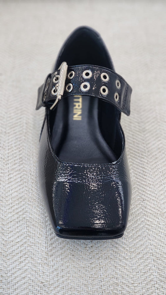 Zapato plano en charol negro con hebilla metálica ancha.